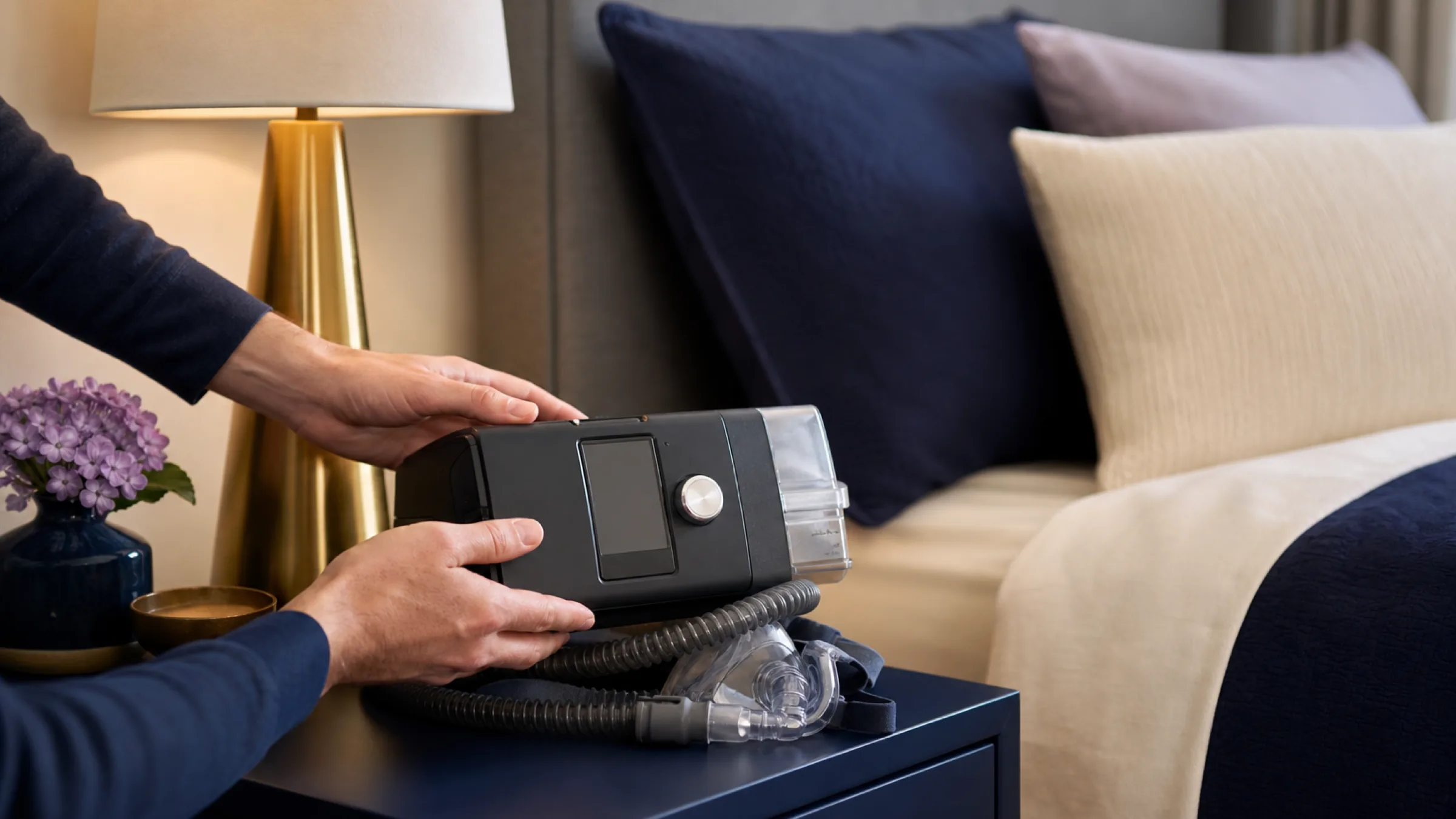 Auto CPAP machine being placed on a bedside table
